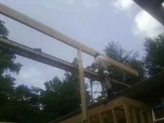 Carpenter setting a ridge beam over a new addition frame — Ice Dam Removal by Roofing Brothers in Stella