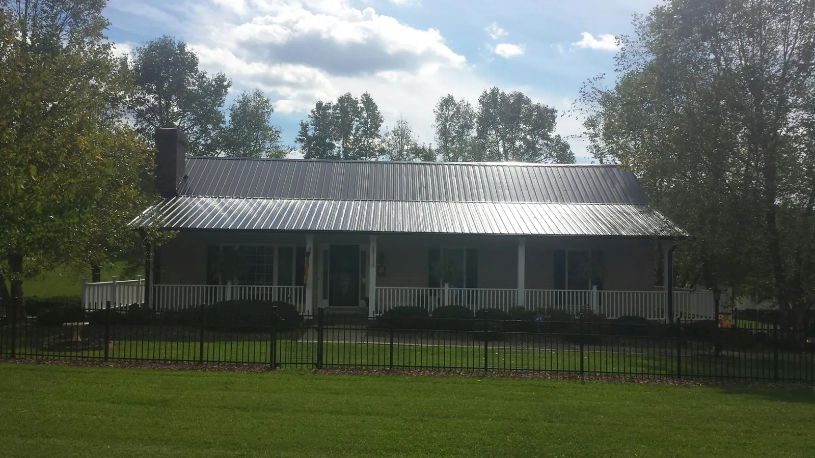 Gray metal roof on a brick ranch with a full width front porch — Gutter Guard Installation work by our crew in Stella